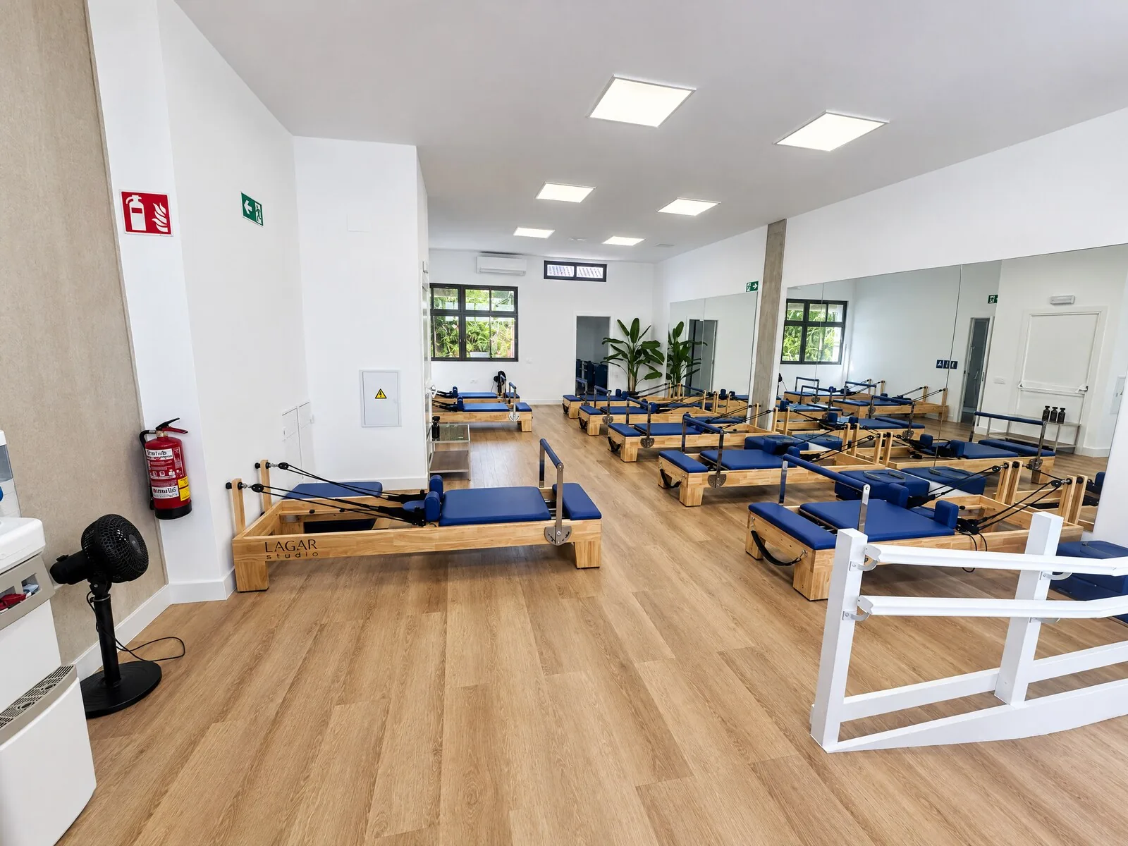 Sala reformer desde la entrada, con la barandilla blanca y la planta junto a la ventana — Lagar Studio Aravaca